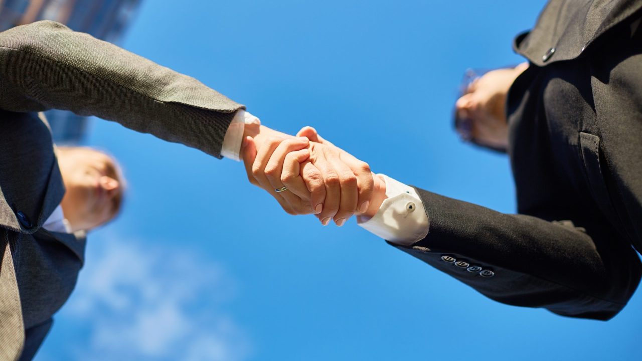 Handshake of partners and blue sky above